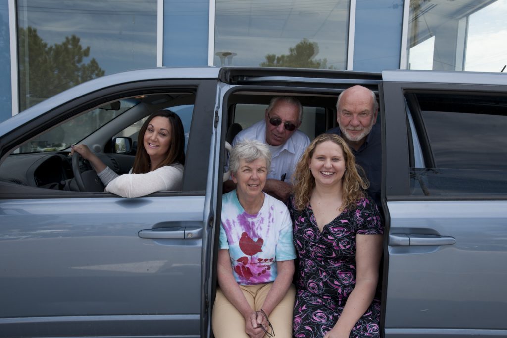 A family sitting in a grey minivan