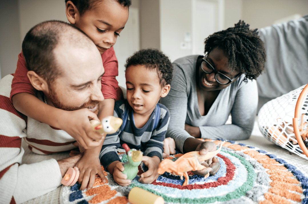 Interracial family of four playing with dinosaurs