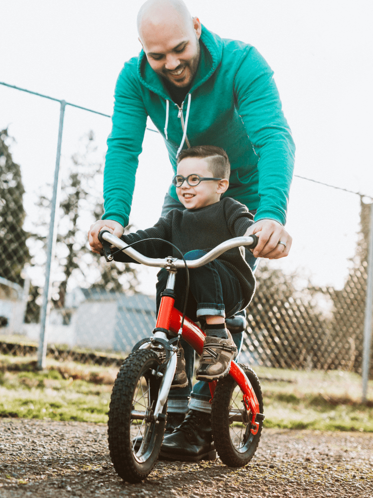 Dad helping toddler son how to ride a bicycle